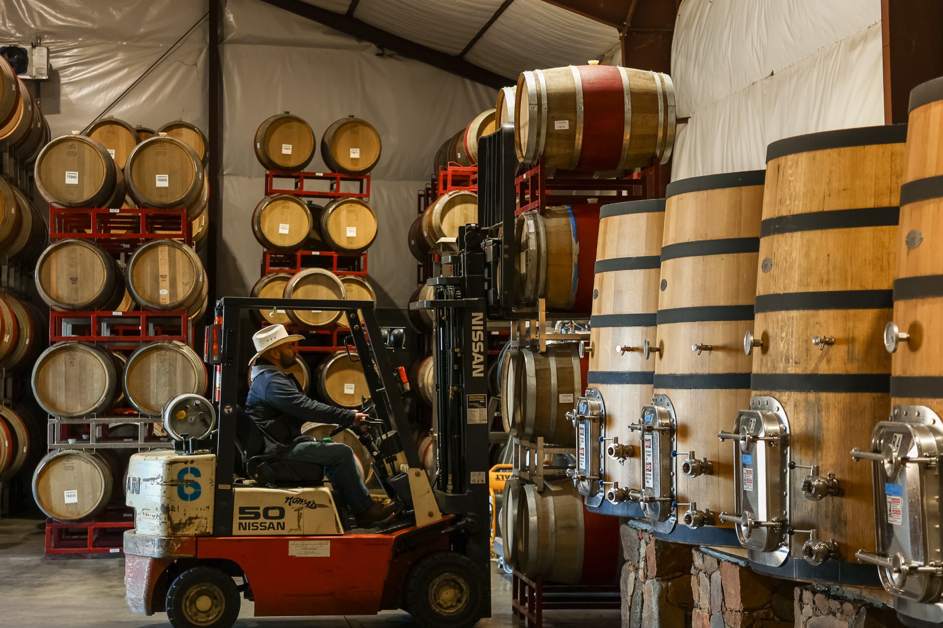 Isy Borjon using a forklift moving wine barrels in the cellar.